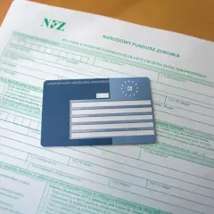Wniosek o EKUZ. Ile się czeka na kartę? Dokumenty i karta ubezpieczenia zdrowotnego leżą na stole.