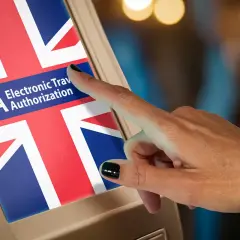 Dłoń dotyka ekranu z flagą Wielkiej Brytanii i napisem ETA Electronic Travel Authorization. To krok do uzyskania wizy do Anglii.