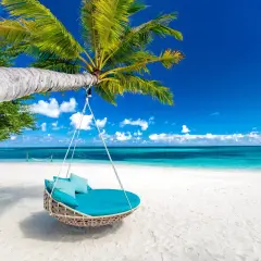 Huśtawka z poduszkami na plaży, idealna na malediwy loty. Błękitne niebo, turkusowa woda i biały piasek.