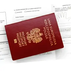 Polski paszport na tle wniosku. Dokument jest niezbędny do podróży do wielu krajów poza Unią Europejską.