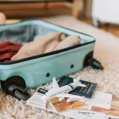 Bagaż Electra Airways gotowy do podróży: walizka, ubrania, paszporty, bilety i miniaturowy samolot.