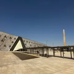 Nowoczesne muzeum egipskie z obeliskiem w tle, pod błękitnym niebem.