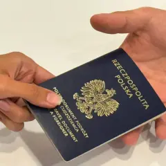 Dłoń przekazuje paszport Rzeczypospolitej Polskiej. Ważność paszportu jest kluczowa dla podróży.
