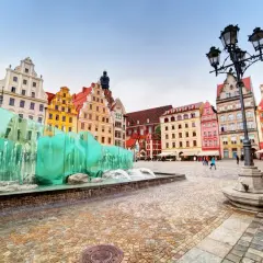 Kolorowe kamienice na Rynku we Wrocławiu, jednym z najładniejszych miast w Polsce, przy nowoczesnej fontannie.