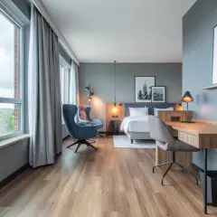 Nowoczesny pokój w **Radisson Blu Hotel Rostock** z widokiem na miasto, łóżkiem, fotelem i biurkiem.