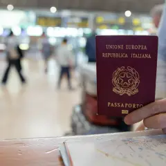 Włoski paszport w dłoni, na tle lotniska. Czy do Finlandii potrzebny jest paszport? Tak, jeśli nie jesteś obywatelem UE.