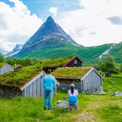 Para podróżuje po Norwegii, podziwiając tradycyjne chaty z zielonymi dachami i majestatyczne góry. Czy do Norwegii potrzebny jest paszport? Zależy od Twojego obywatelstwa.
