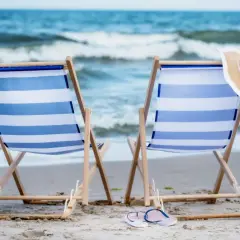 Dwa leżaki na plaży, gotowe na idealny weekend nad morzem. W tle widać morze i fale.