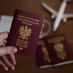 Dłoń trzyma polski paszport. Obok leżą inne paszporty, maseczka i samolot. Zastanawiasz się, ile trwa wyrobienie paszportu?
