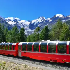 Czerwony pociąg Bernina Express w malowniczej scenerii Alp. Wycieczka przez góry z widokiem na ośnieżone szczyty i zielone lasy.
