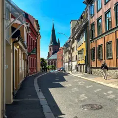 Ulica w Oslo z kolorowymi kamienicami i kościołem w tle.