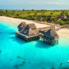 Willa na palach nad turkusową wodą, idealne miejsce na wiza zanzibar. Piękna plaża i bujna zieleń w tle.