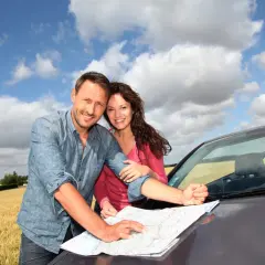 Para planowania podróży za granicę krótkoterminowe, para z mapą przy samochodzie w słoneczny dzień.