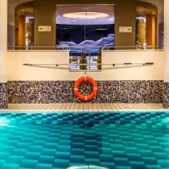 Basen w Radisson Blu Szczecin. Błękitna woda, mozaikowa ściana i rzeźba w tle.