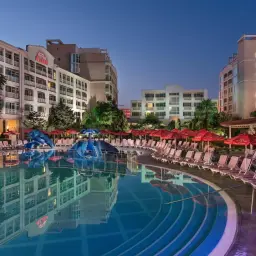 Basen i leżaki przy hotelu Alba w Bułgarii. Wieczorna atmosfera z oświetlonymi budynkami i basenem.