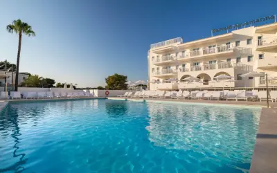 Basen z turkusową wodą i leżakami przy hotelu Barceló Aguamariina. Wysoka palma dodaje tropikalnego klimatu.