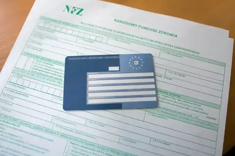 Wniosek o EKUZ. Ile się czeka na kartę? Dokumenty i karta ubezpieczenia zdrowotnego leżą na stole.