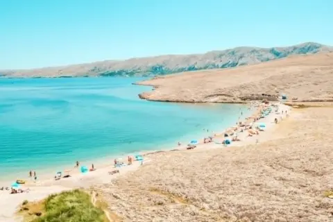 Turkusowe jakie morze jest w Chorwacji? Piękna plaża z ludźmi, parasolami i górami w tle.