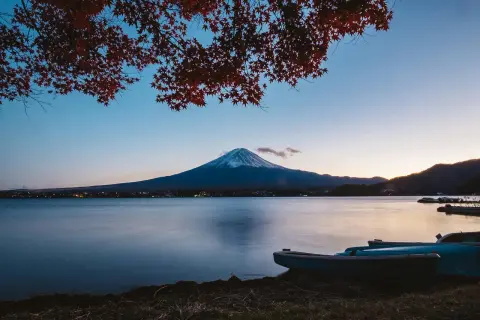 Zachód słońca nad jeziorem z łodziami i górą Fudżi w tle. Zastanawiasz się, ile się leci do Japonii, patrząc na ten widok?