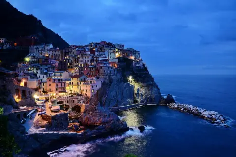 Kolorowe domy Cinque Terre, wspaniałe włochy regiony turystyczne, oświetlone nocą nad morzem.