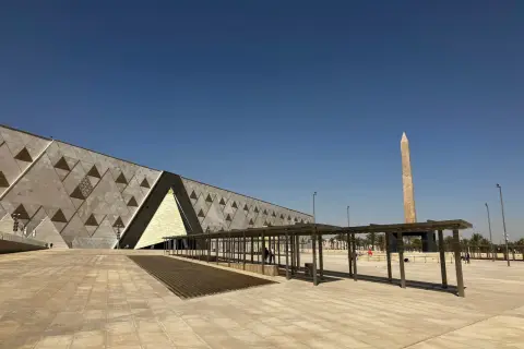 Nowoczesne muzeum egipskie z obeliskiem w tle, pod błękitnym niebem.
