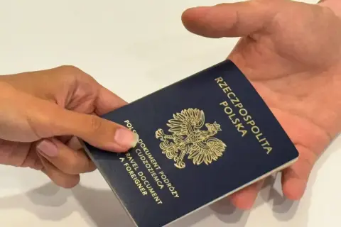Dłoń przekazuje paszport Rzeczypospolitej Polskiej. Ważność paszportu jest kluczowa dla podróży.