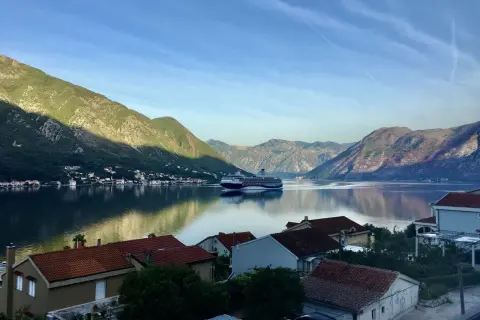 Widok na zatokę w Czarnogórze z górami w tle i statkiem wycieczkowym. Czy Czarnogóra jest bezpieczna? Tak, to spokojne miejsce na wakacje.