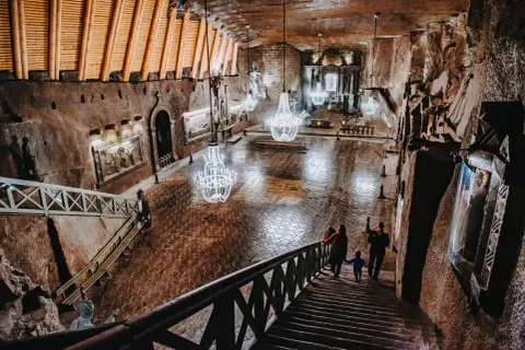 Rodzina schodzi schodami do podziemnej kaplicy w Kopalni Soli "Wieliczka". Bilety do tego cudu natury i sztuki warto kupić wcześniej.