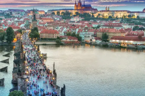Praga nocą, tłumy na Moście Karola. Idealne miejsce na tanie wycieczki objazdowe po Europie.