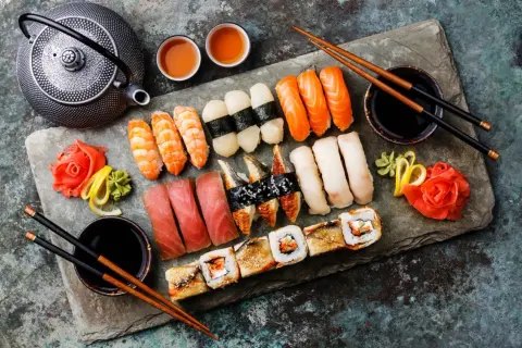 Bogactwo japońskiego jedzenia: sushi z łososiem, tuńczykiem, krewetkami, węgorzem, a także rolki i tradycyjny czajniczek.