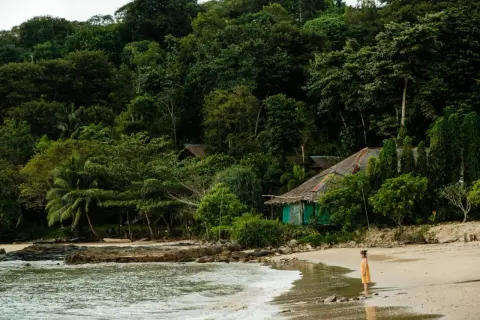 Dziewczynka w żółtej sukience na plaży w Tajlandii, myśląca o szczepieniach przed podróżą.