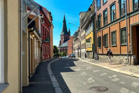 Ulica w Oslo z kolorowymi kamienicami i kościołem w tle.