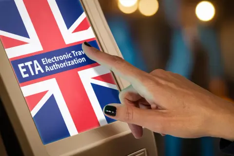 Czy do Anglii potrzebny jest paszport? Ekran z flagą Wielkiej Brytanii i napisem ETA Electronic Travel Authorization, na który wskazuje palec.