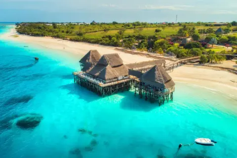 Willa na palach nad turkusową wodą, idealne miejsce na wiza zanzibar. Piękna plaża i bujna zieleń w tle.