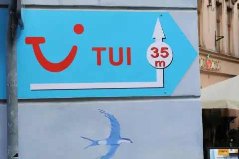 Niebieski szyld TUI z logo i strzałką wskazuje drogę do biura podróży, 35m. Może to być znak, że czas na rezygnację z wycieczki i powrót do domu.