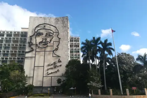 Monumentalny portret Che Guevary zdobi budynek w Hawanie, stolicy Kuby. Obok palm i kubańska flaga.