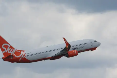 Samolot SkyUp Airlines wznosi się na tle pochmurnego nieba.