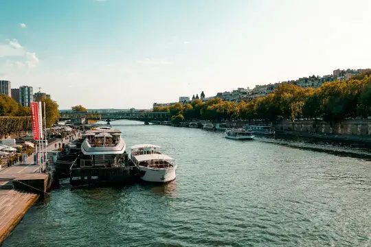 Rejs po Sekwanie to idealny sposób na podziwianie Paryża. Statki cumują przy brzegu, a w tle widać miasto.