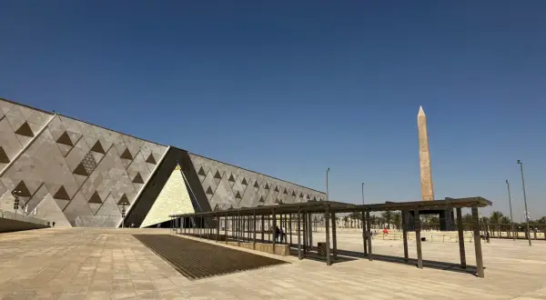 Nowoczesne muzeum egipskie z obeliskiem w tle, pod błękitnym niebem.