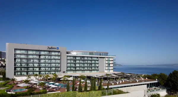 Nowoczesny hotel Radisson Blu Split z basenami i tarasami, położony nad błękitnym morzem.