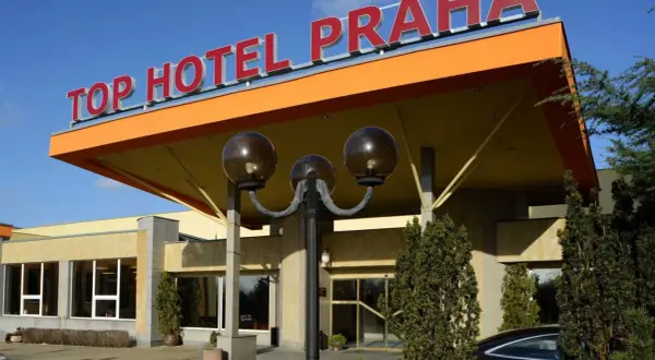 Wejście do TOP HOTEL PRAGA z charakterystycznym, pomarańczowym zadaszeniem i czerwonym napisem.