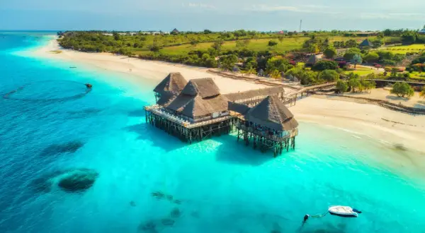 Willa na palach nad turkusową wodą, idealne miejsce na wiza zanzibar. Piękna plaża i bujna zieleń w tle.