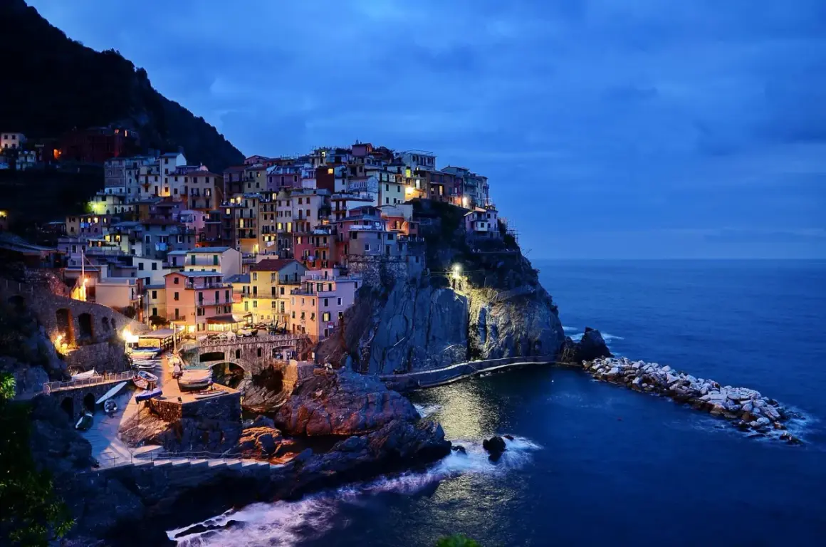Kolorowe domy Cinque Terre, wspaniałe włochy regiony turystyczne, oświetlone nocą nad morzem.