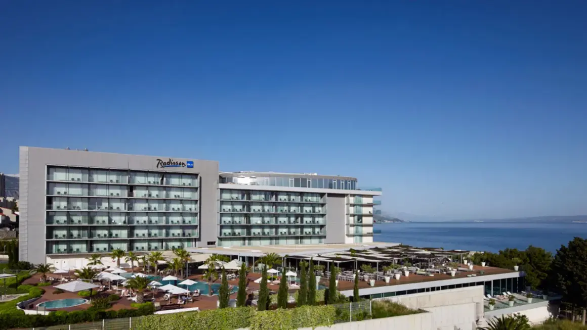 Nowoczesny hotel Radisson Blu Split z basenami i tarasami, położony nad błękitnym morzem.