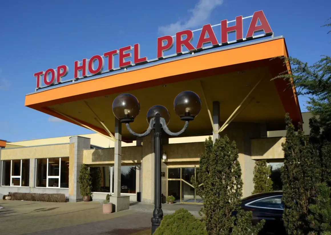 Wejście do TOP HOTEL PRAGA z charakterystycznym, pomarańczowym zadaszeniem i czerwonym napisem.