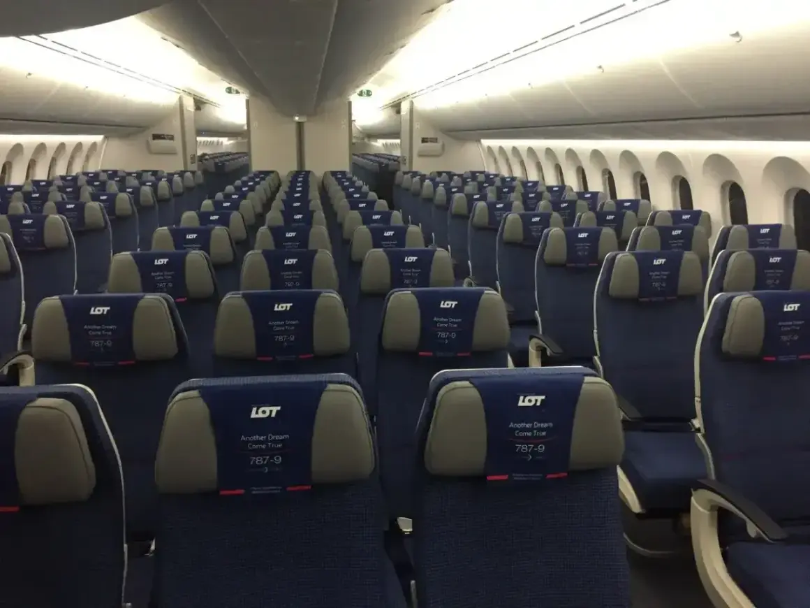 Puste siedzenia w samolocie LOT Dreamliner. Widok na rzędy niebieskich foteli z zagłówkami LOT 787-9.