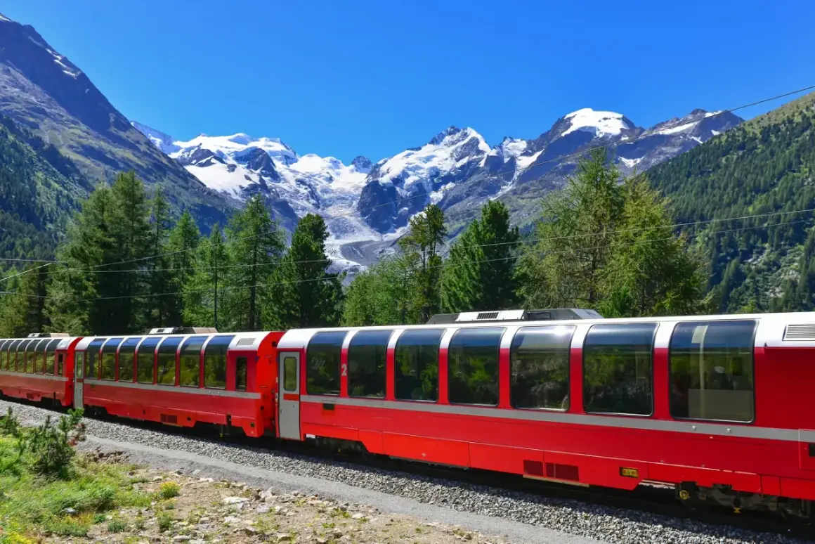 Czerwony pociąg Bernina Express w malowniczej scenerii Alp. Wycieczka przez góry z widokiem na ośnieżone szczyty i zielone lasy.