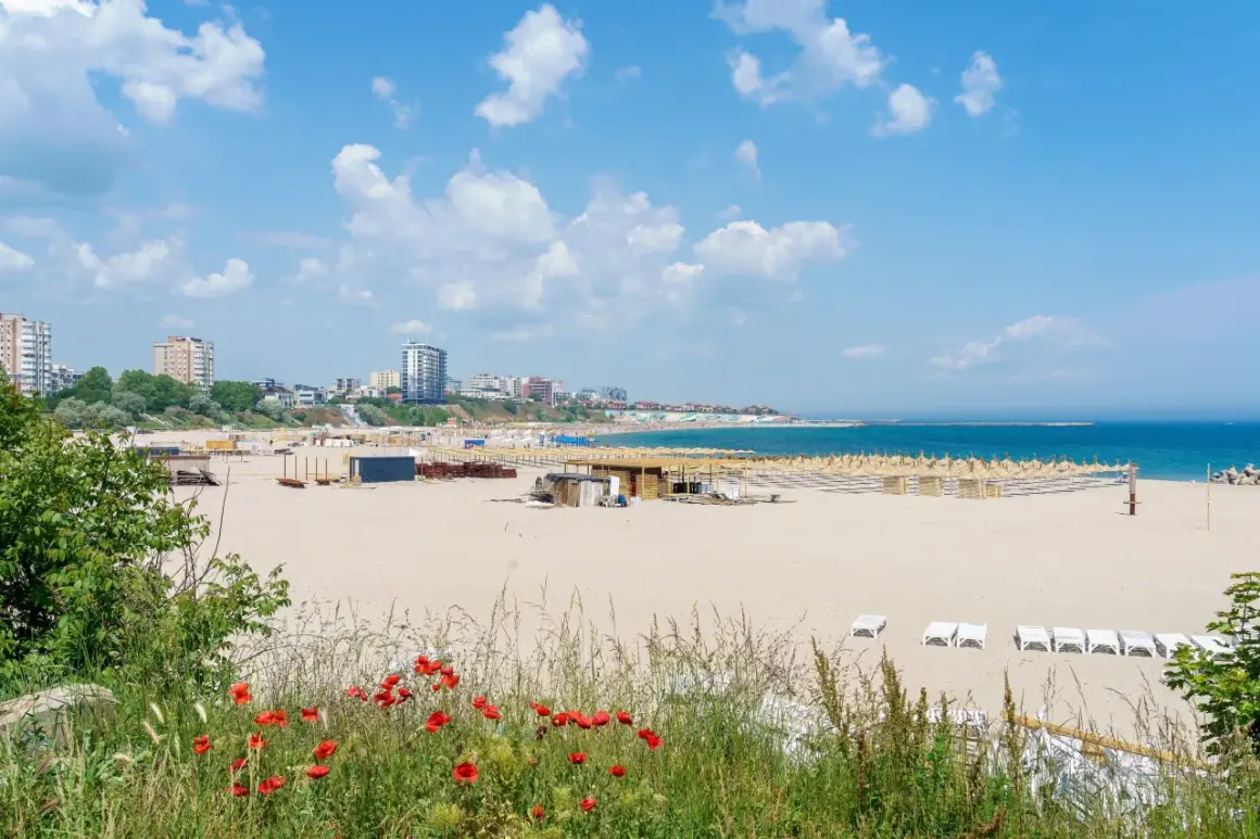Piękne, puste plaże w Rumunii, z rzędami leżaków i parasoli, w tle budynki mieszkalne i błękitne morze.