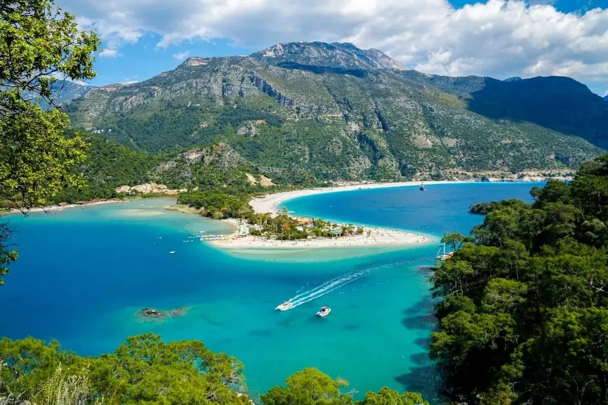 Malownicze wybrzeże Turcji z turkusową wodą, piaszczystą plażą i górami w tle. Idealne miejsce na wakacje w jednym z pięknych miast w Turcji.