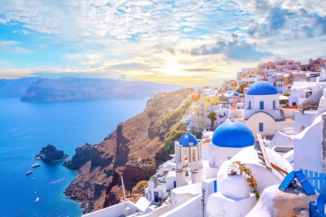 Malownicze greckie miasta na Santorini, z białymi domami i niebieskimi kopułami kościołów, górują nad turkusowym morzem.